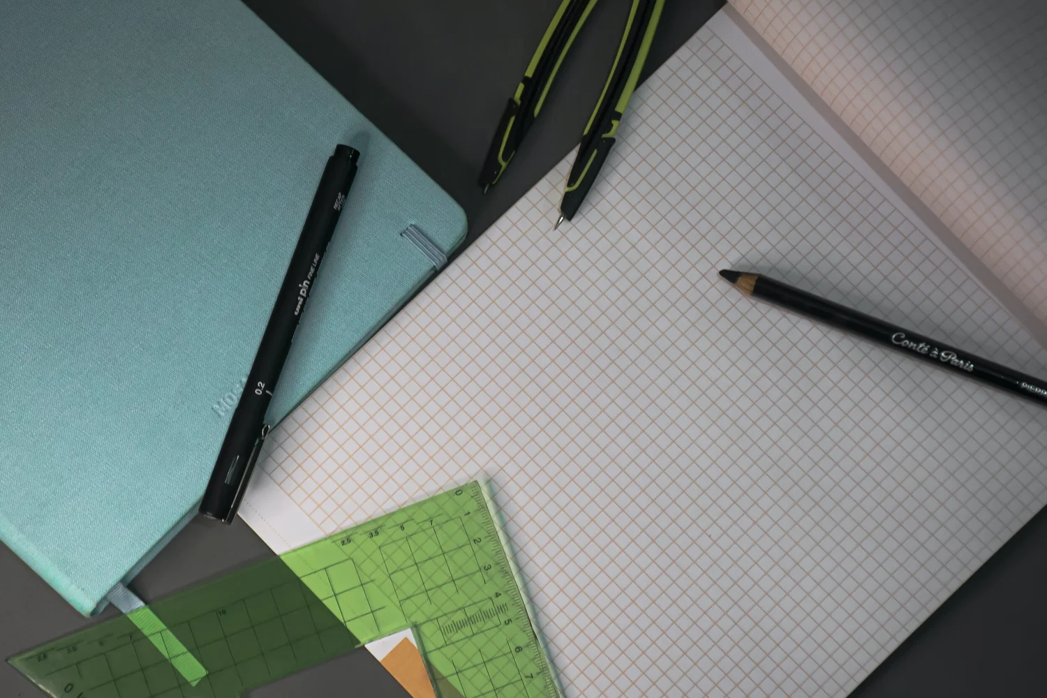 Grid notebook, pens, and ruler on a desk